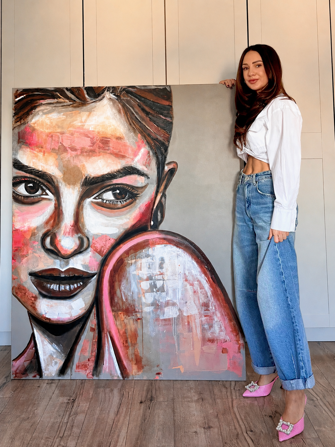 Mező Mariann festőművész a 150x120 cm-es, monumentális méretű The Girl I left Behind című akril és olaj alkotása mellett, bemutatva a kép valódi arányait.